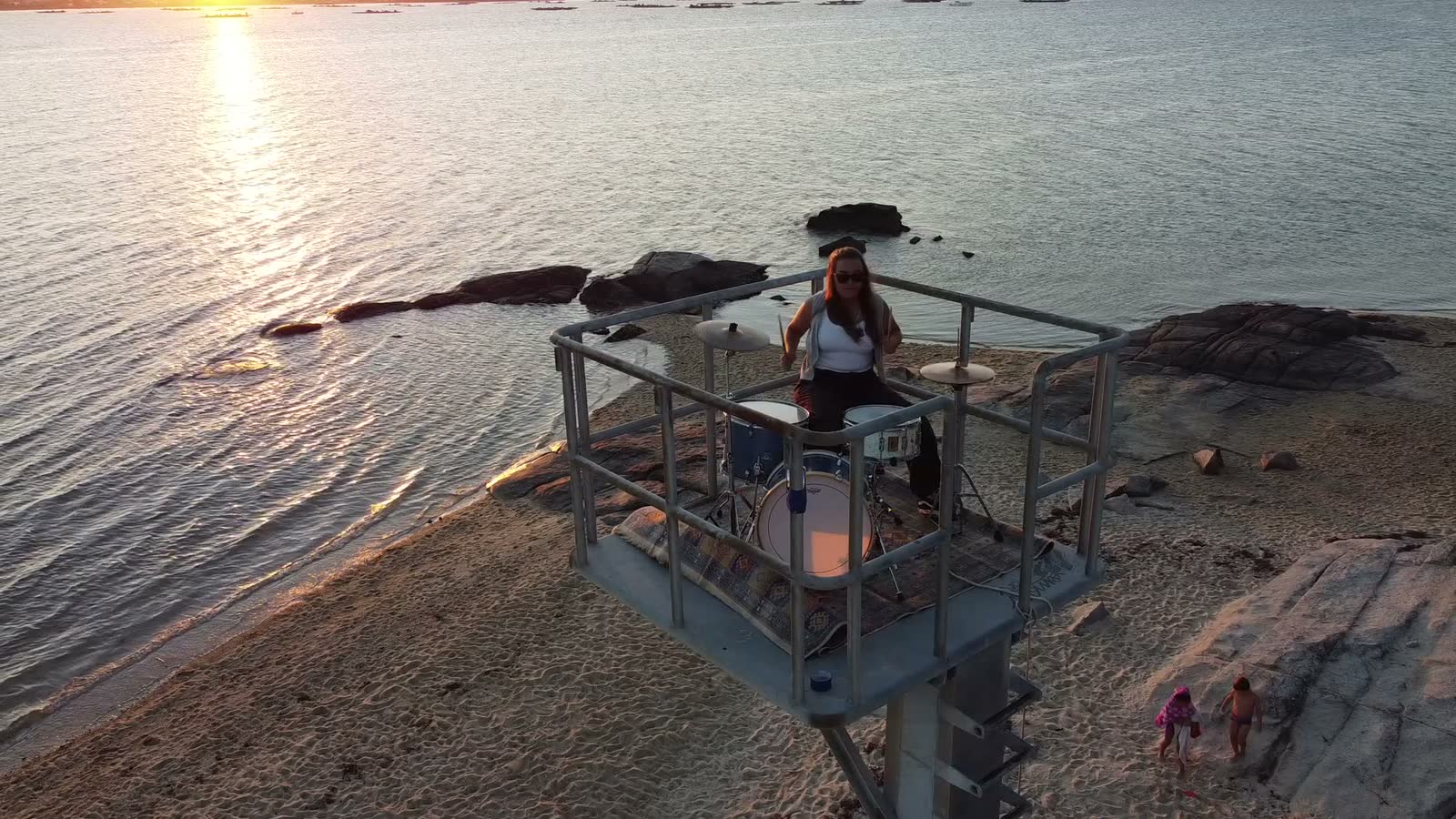 Sira Goyanes tocando la batería sobre una plataforma en el mar, al atardecer